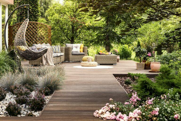 terrasse en bois avec un salon en rotin et un jardin autour